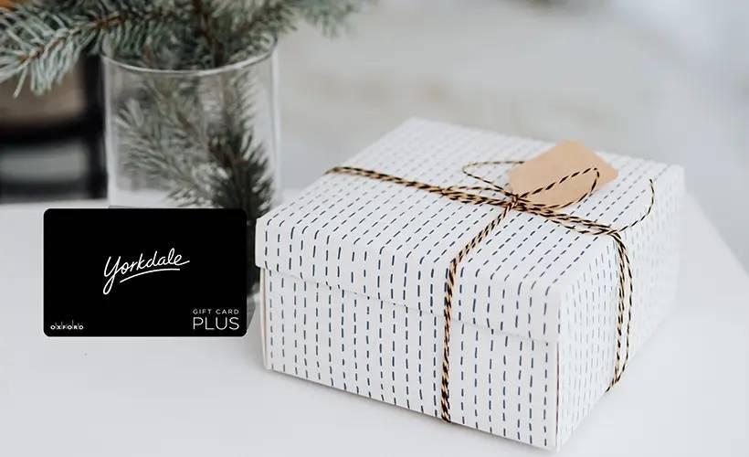 Yorkdale Gift Card Plus beside a white wrapped gift box tied with twine