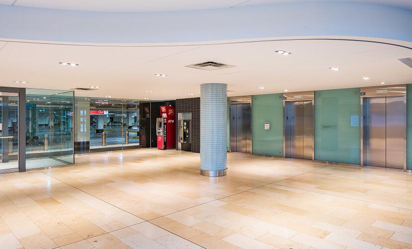 Mall lower level with ATM kiosk, elevator banks, and glass exterior doors