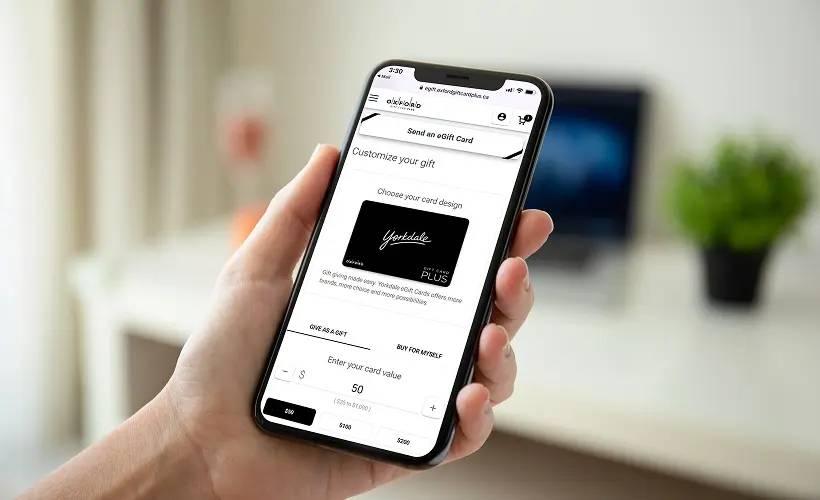 Hand holding smartphone showing Yorkdale eGift Card purchase customization page