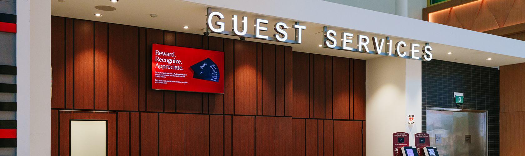 Yorkdale Guest Services counter with gift card kiosks and a digital screen