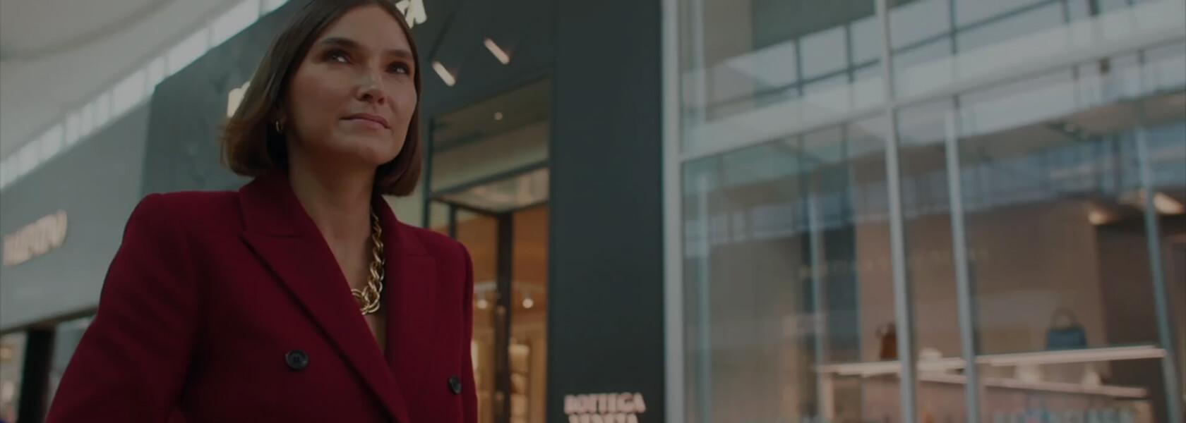 Woman in red blazer and gold chain necklace walking past Bottega Veneta at Yorkdale