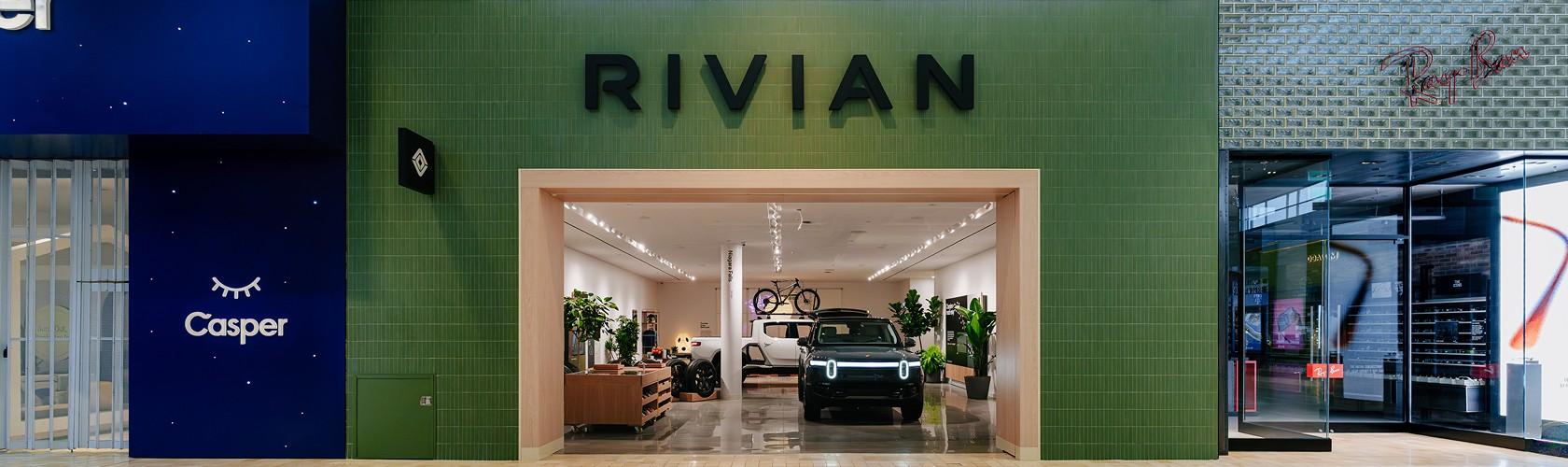 Electric vehicle showroom with SUVs and a bicycle display inside a green storefront