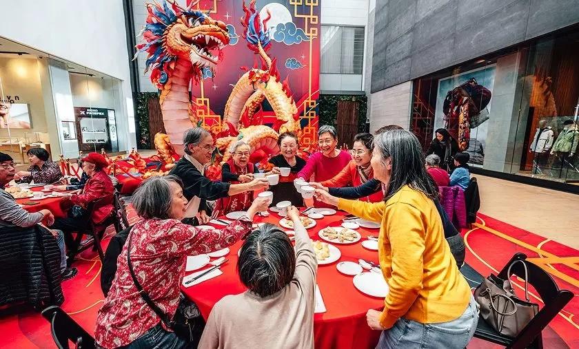 Family and friends toasting at a red table during Lunar New Year celebration in mall