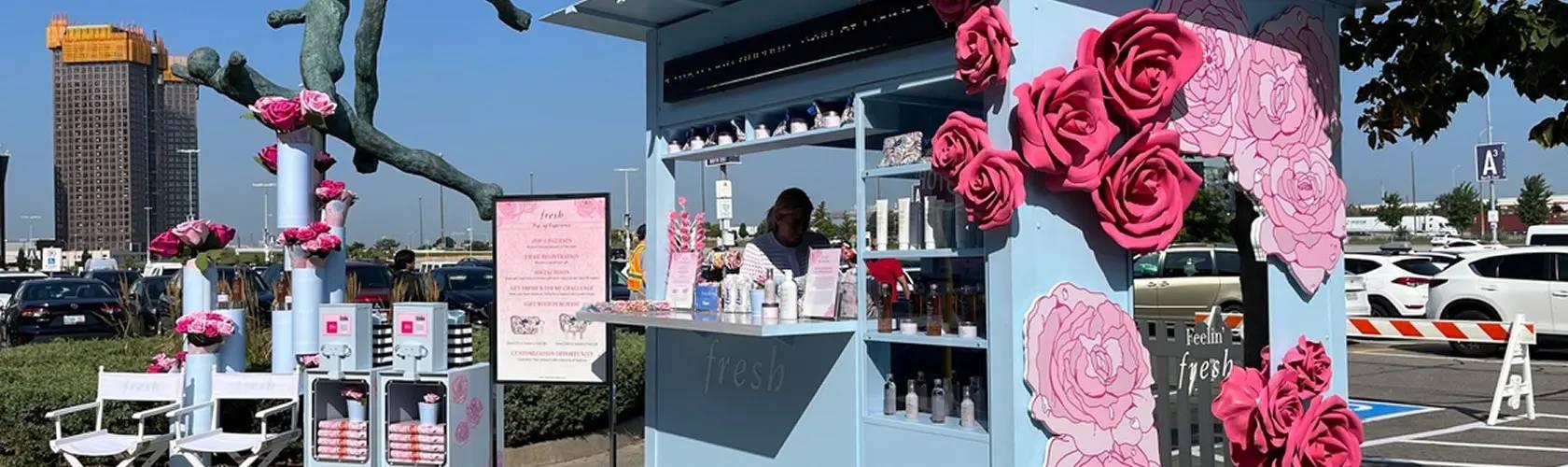 Fresh beauty outdoor pop-up kiosk decorated with large pink roses in parking lot