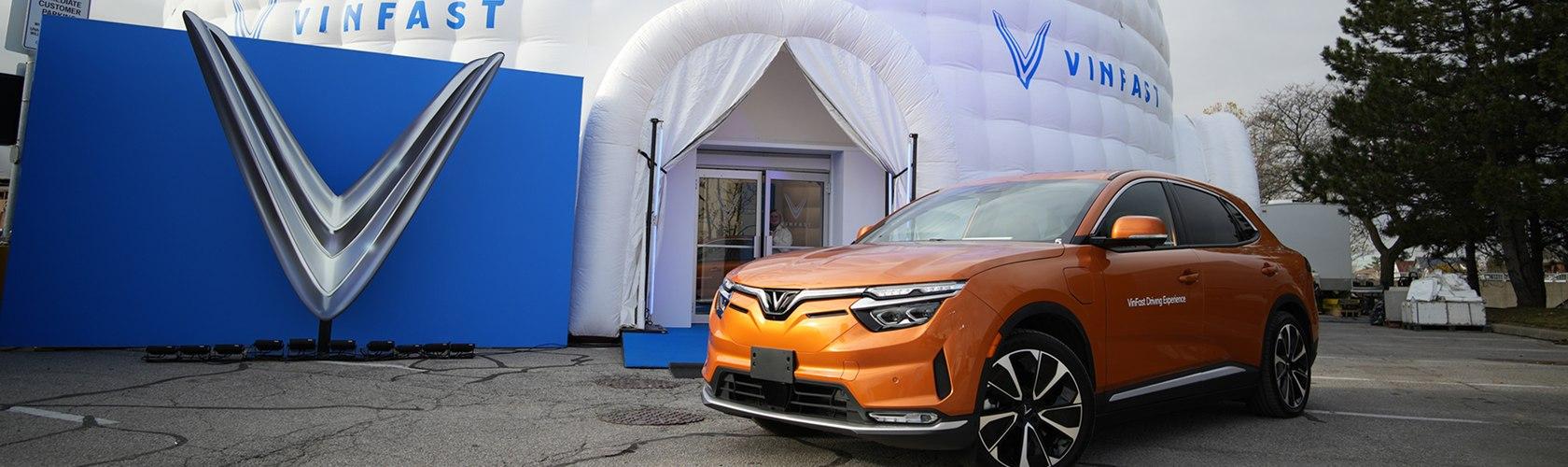 Orange VinFast electric SUV parked in front of an inflatable brand activation tent
