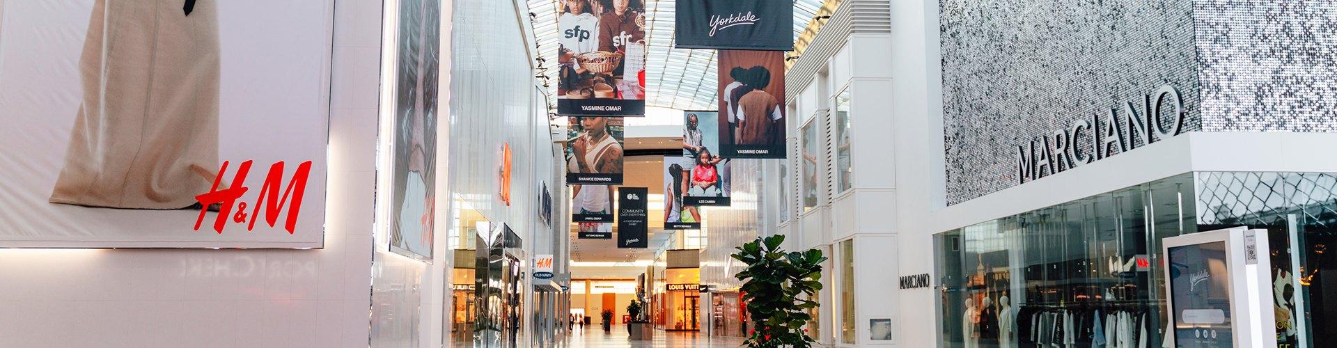 Yorkdale mall corridor with H&M and Marciano stores and community campaign banners