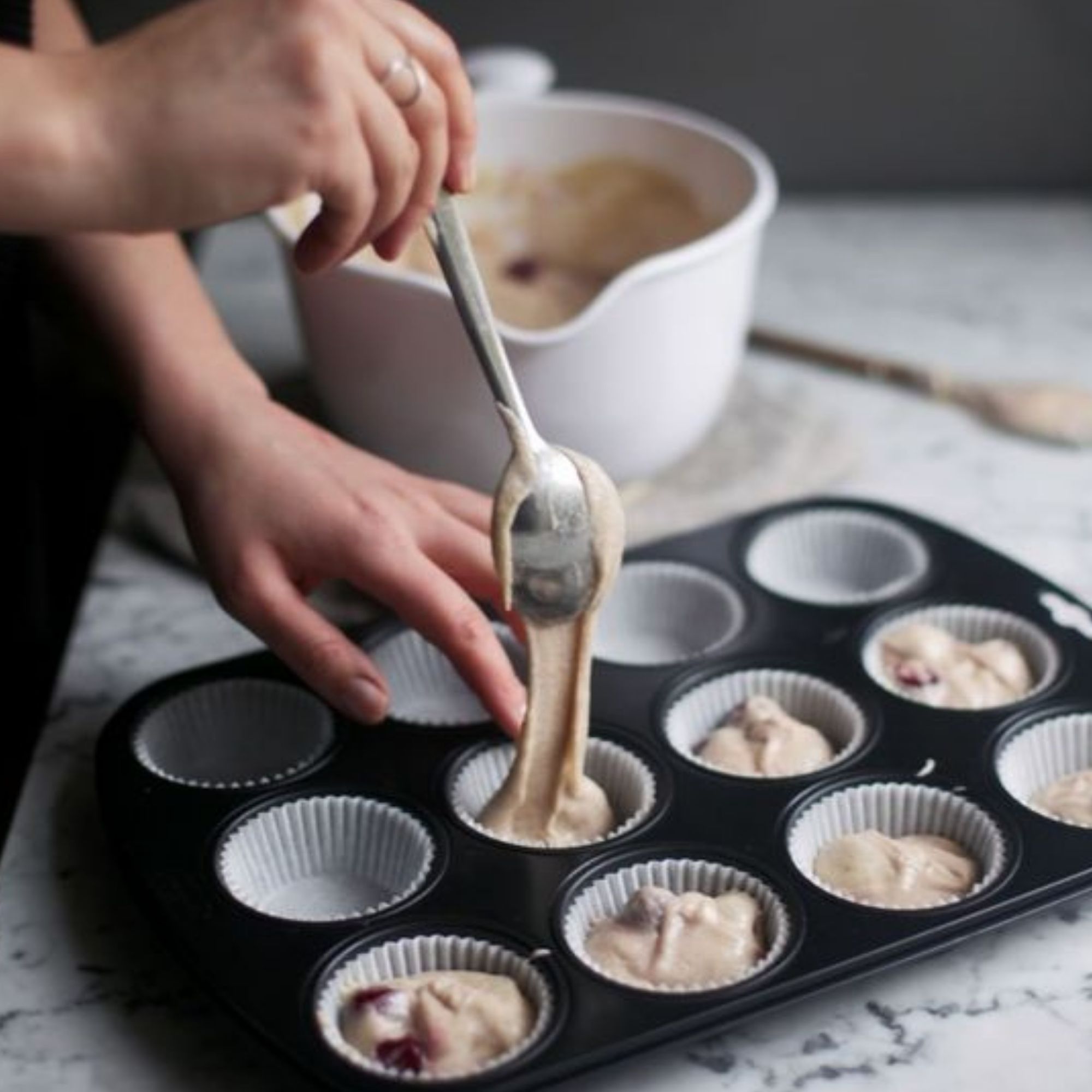 Mixed dough being poured into cupcake tray