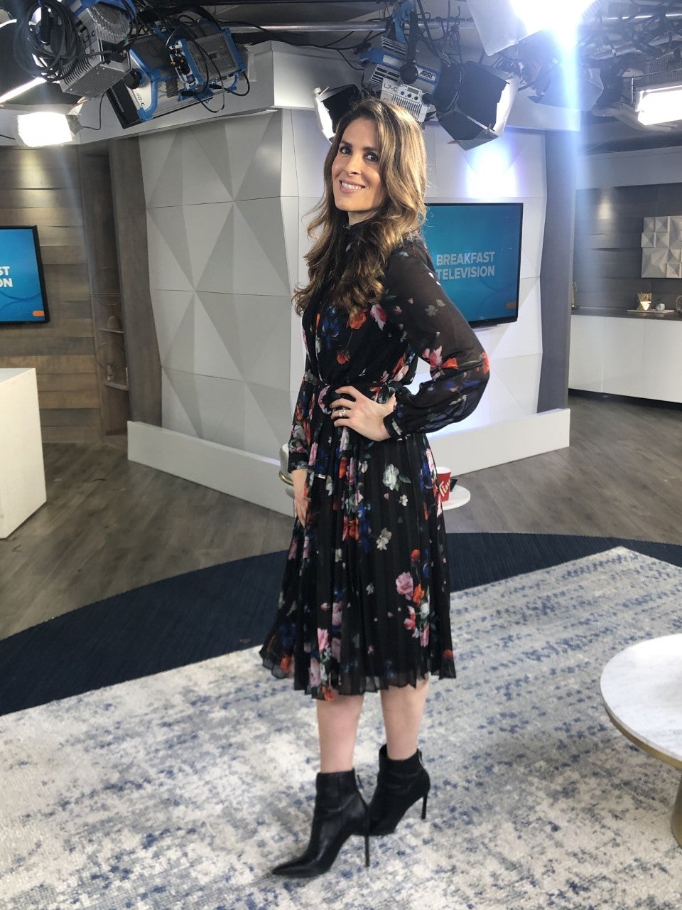 Dina wearing a black floral print dress with black booties