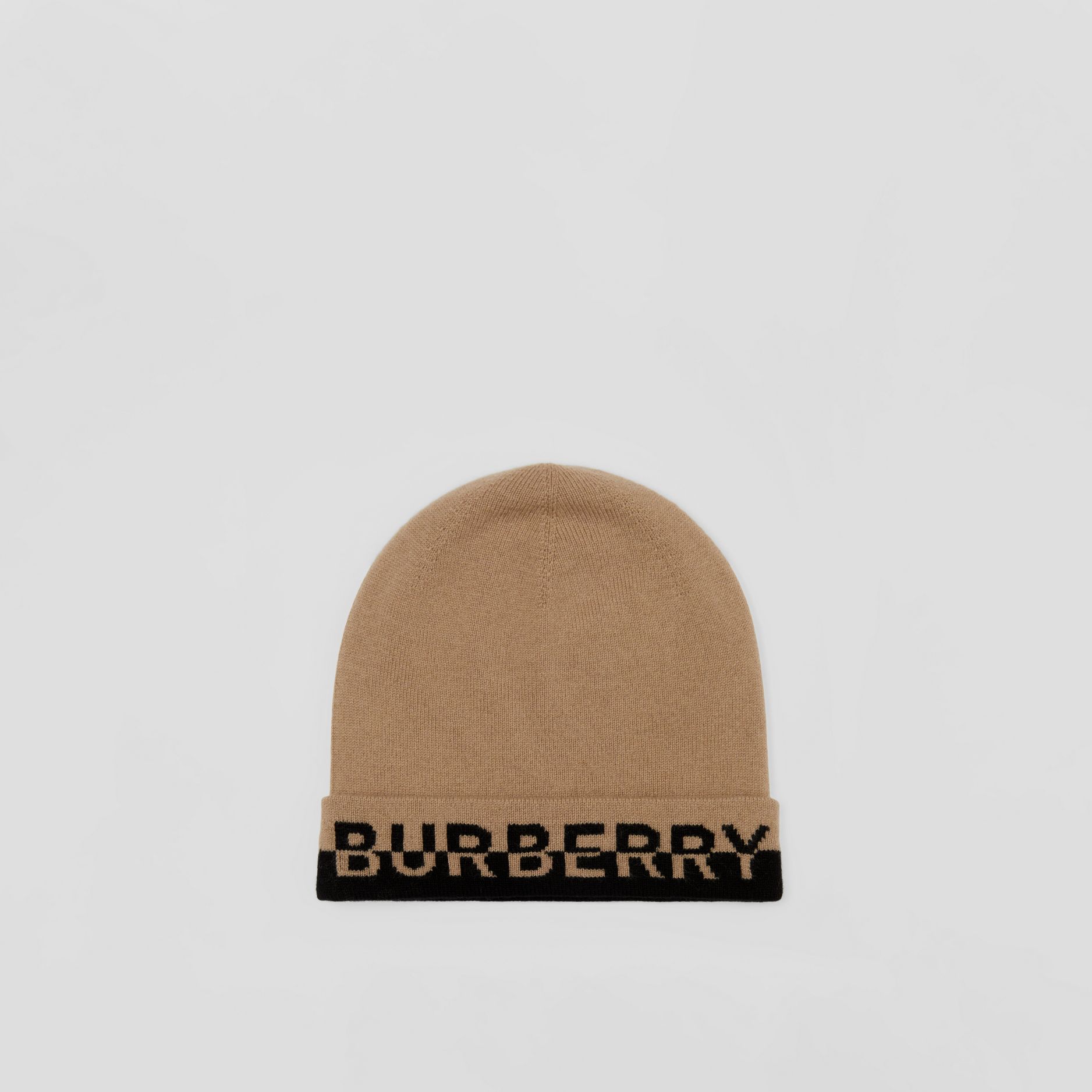 Image of a beige Burberry beanie. The bottom of the hat, closest to the head, is black. The words BURBERRY are written at the base of the hat.