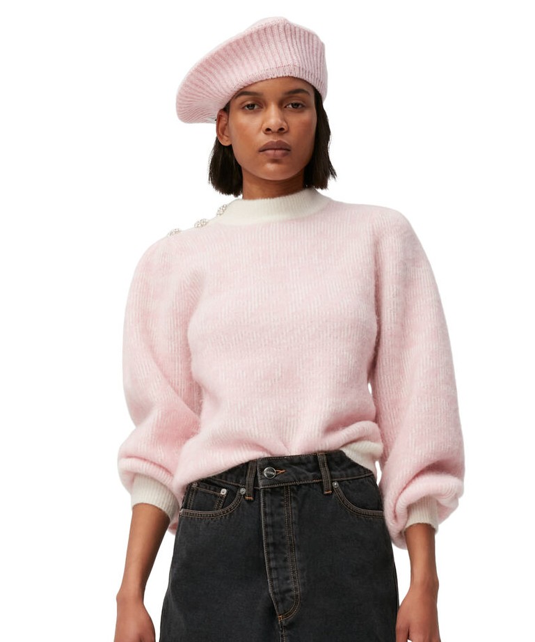 Image of a model wearing a pink GANNI knit sweater and a matching beret. She pairs the look with black jeans.