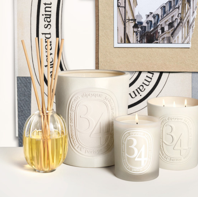 Lifestyle image of an assortment of Diptyque 34 candles in various sizes. A diffuser sits beside them.
