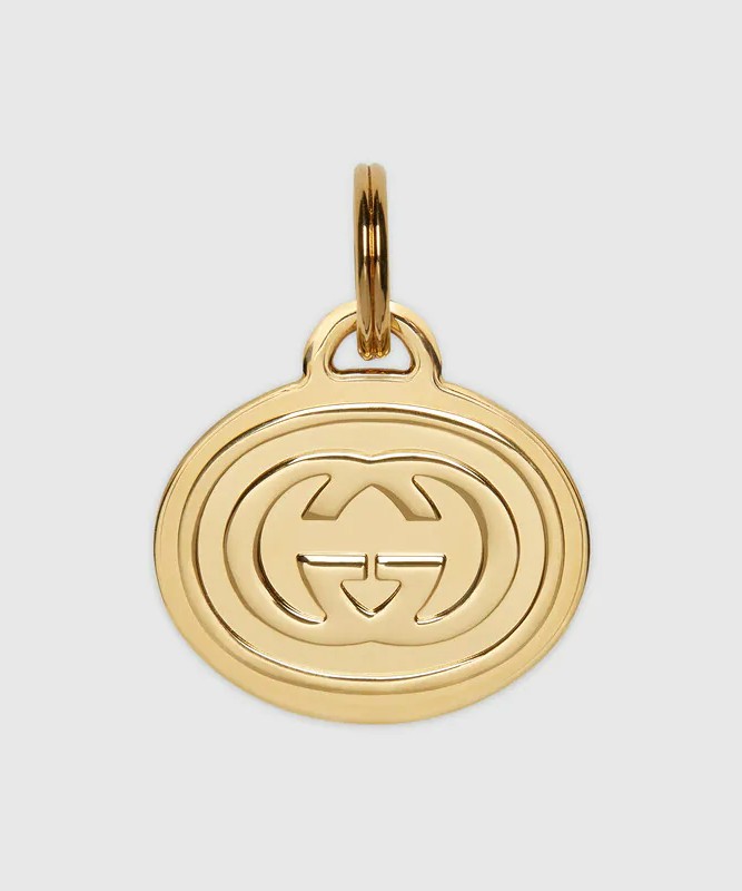 Gucci pet tag made of gold-tone metal and featuring the iconic Gucci log engraved on the front.