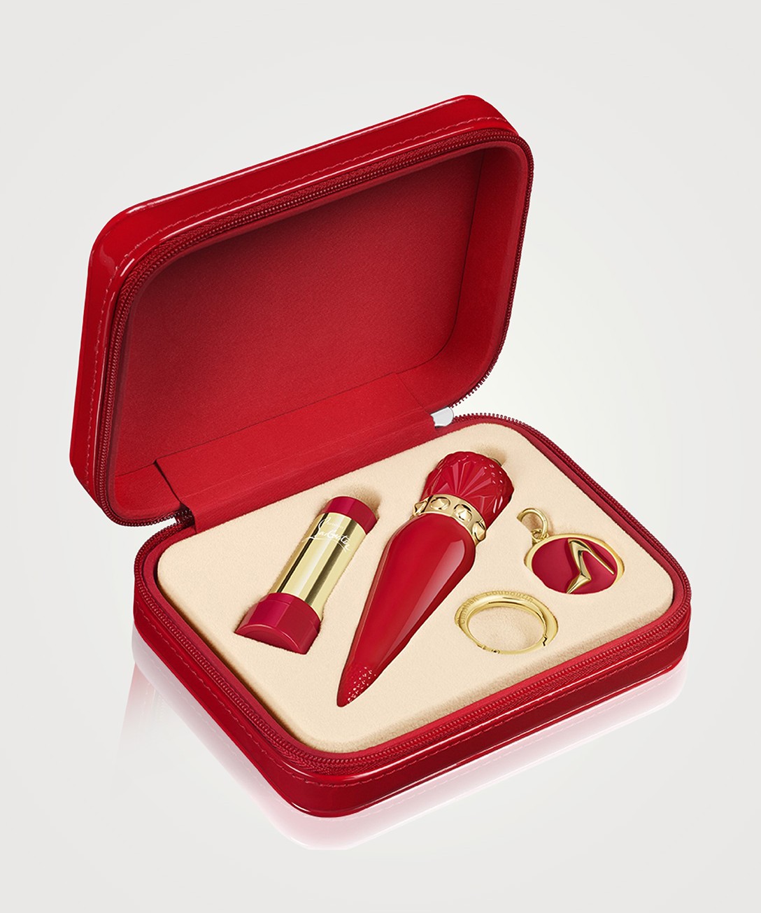A red gift set from Louboutin Beauty with a lipstick, nail polish and keychain featuring a gold stiletto.