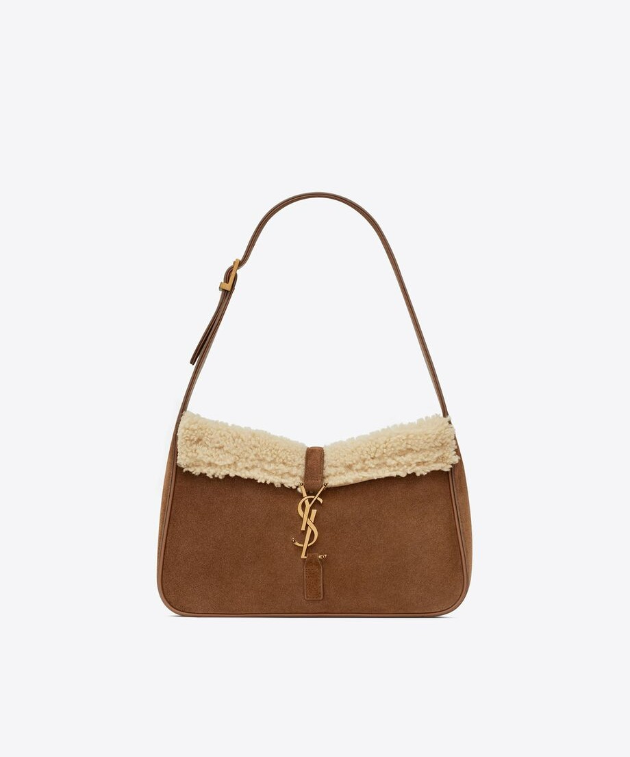 Image of a brown suede Saint Laurent 5 a 7 bag. The bag is a hobo shape and features a shearling lining, visible at the top of the bag. The clasp has the iconic YSL logo in gold.
