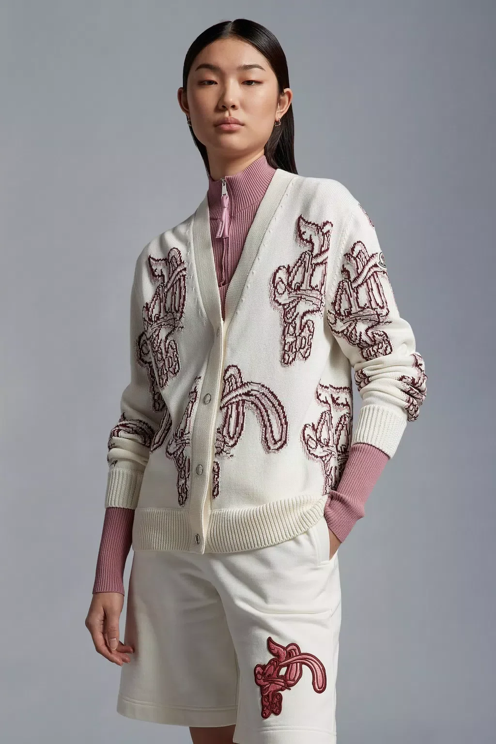 Image of a model wearing a white Monclear cardigan with bunny motifs throughout. She wears matching white shorts with a bunny logo in red.