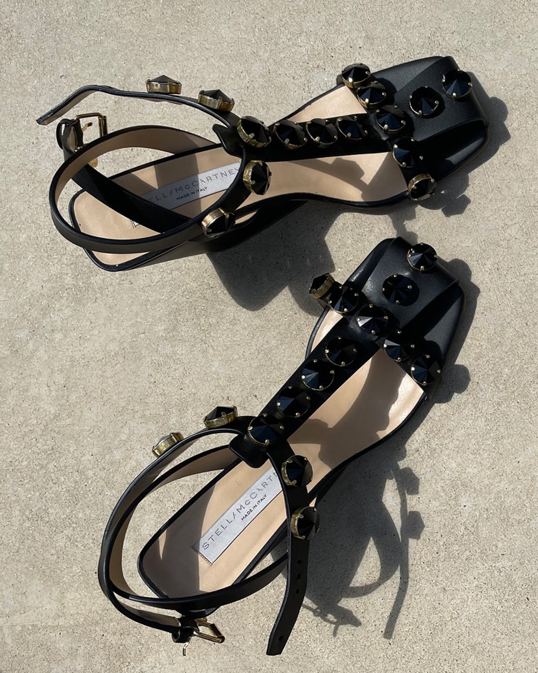 A pair of black, open-towed heels with an ankle strap and raised studded design on the straps throughout.