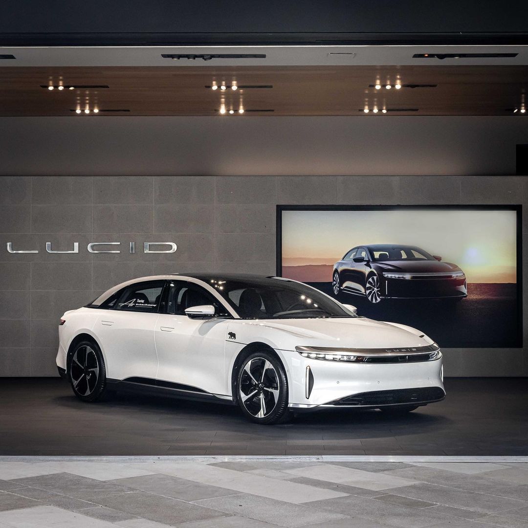 A white electric sedan from Lucid Motors with black wheels and rims.