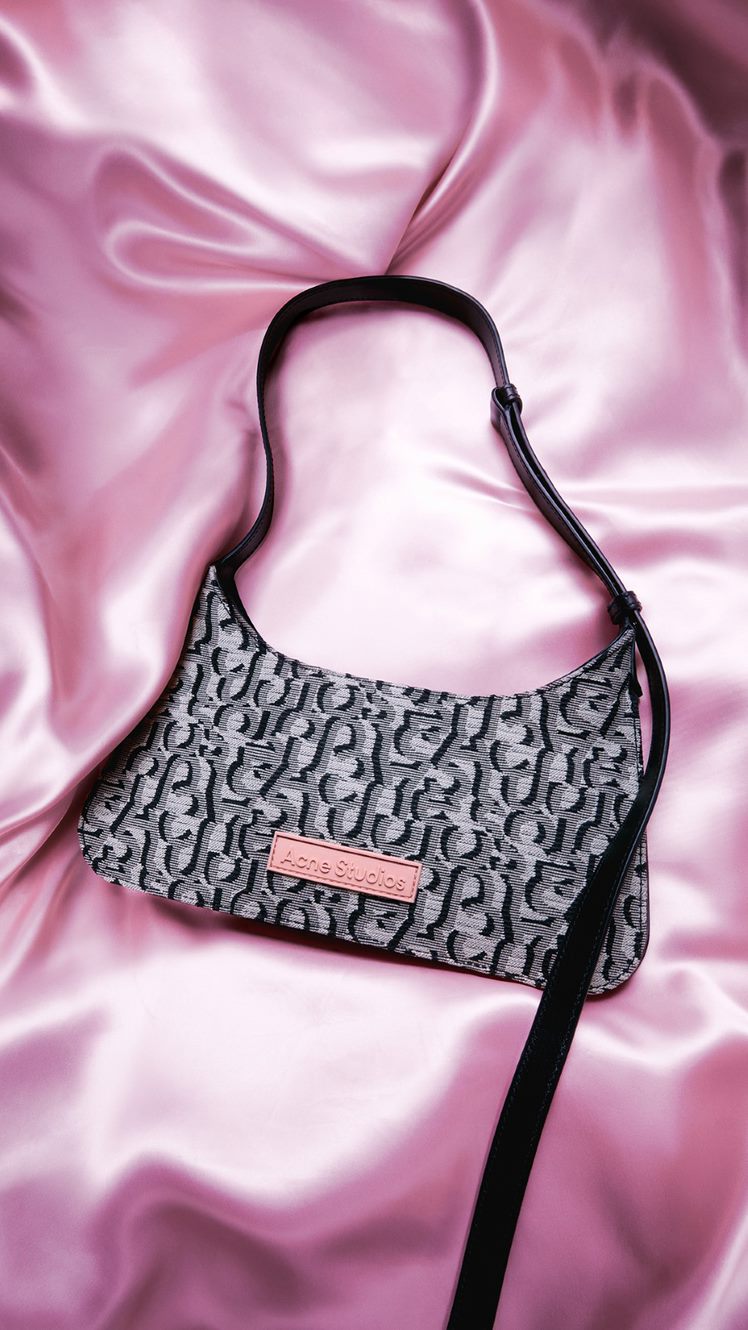Acne bag in front of a pink silk background