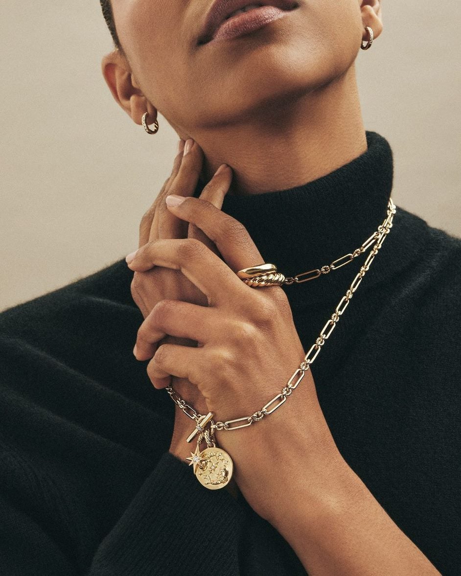 Model wearing a black turtleneck holding layered jewellery