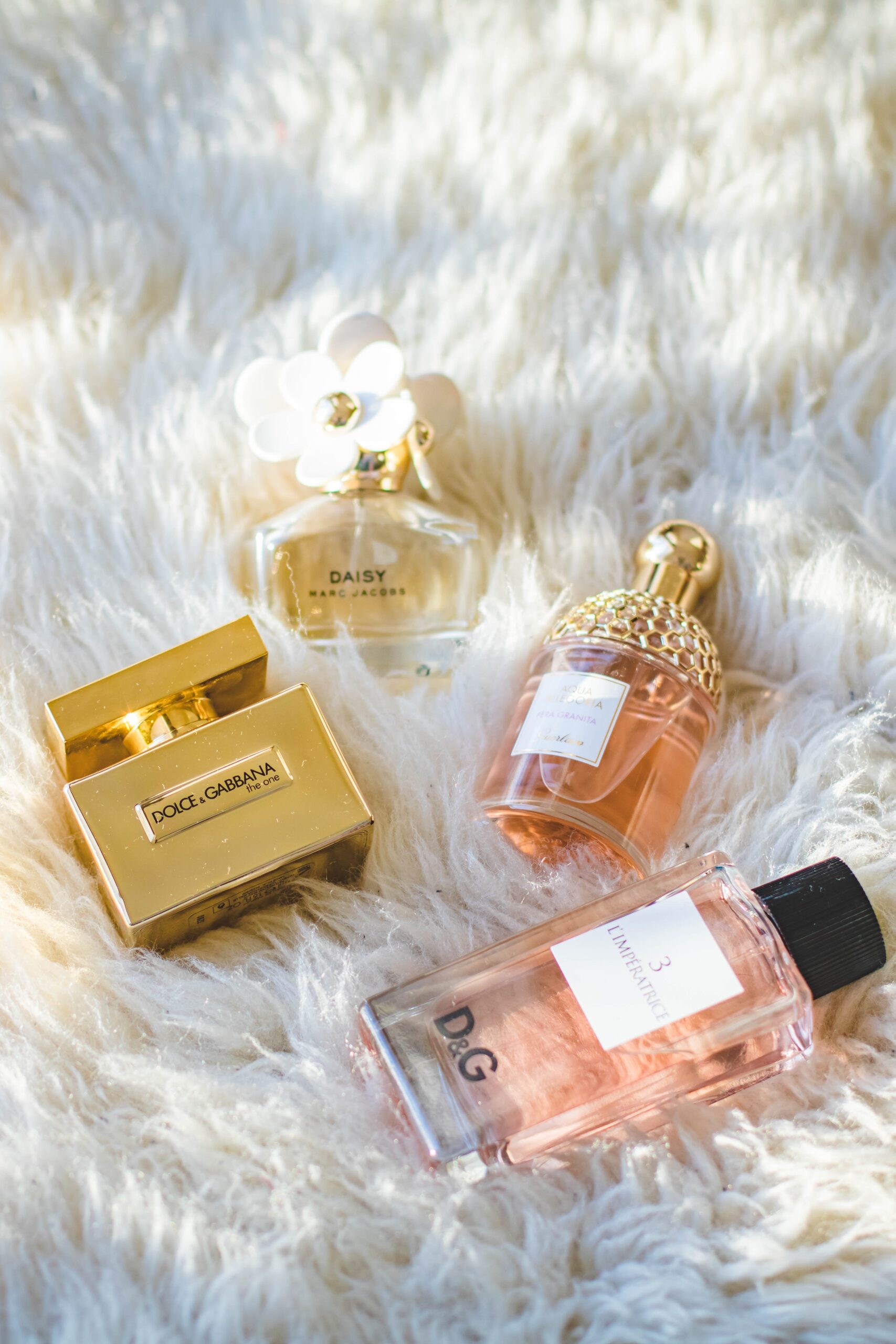 Four bottles of perfume lying on a white textured background.