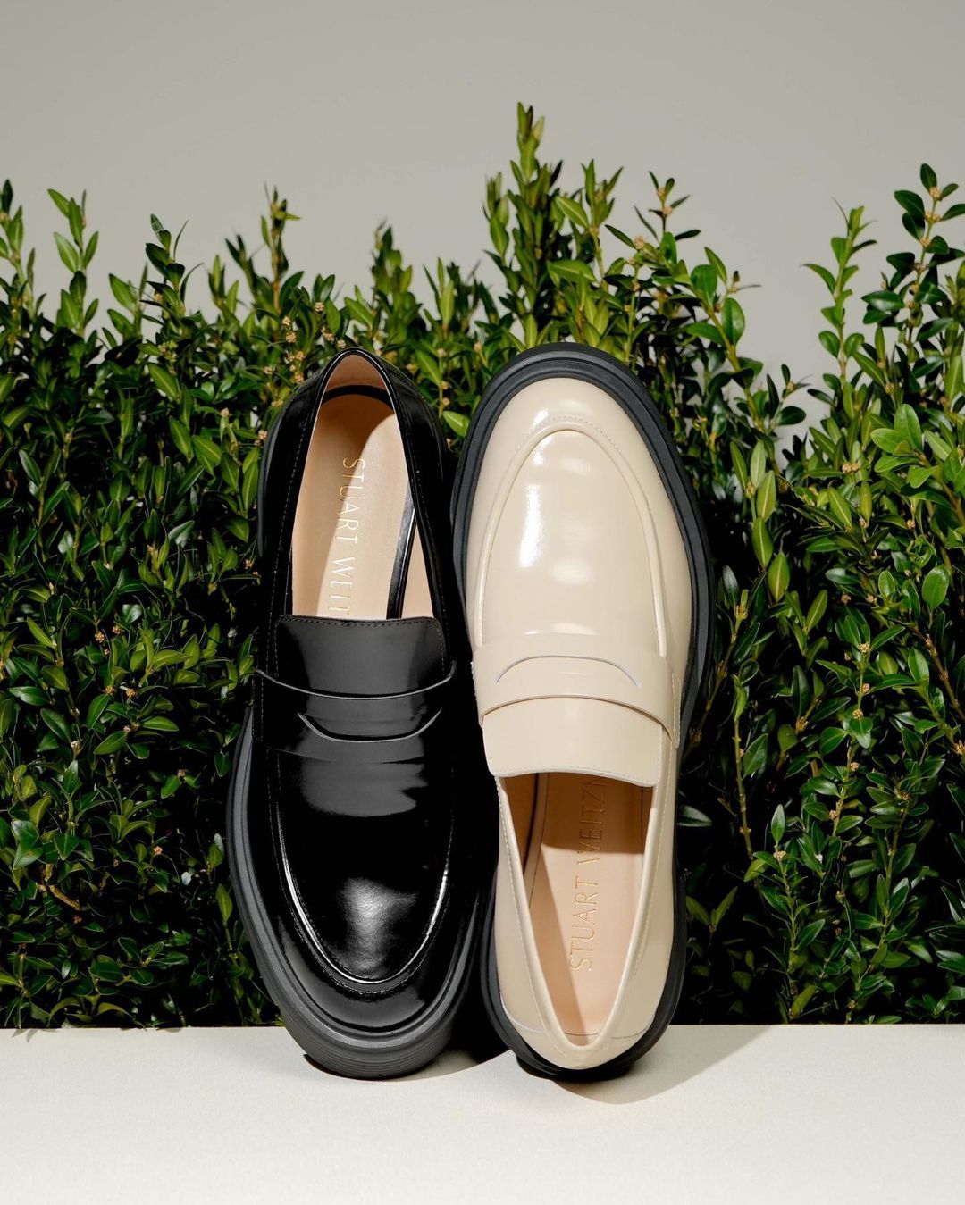 image of two pairs of stuart weitzman loafers. the one on the left is black and the one on the right is cream.