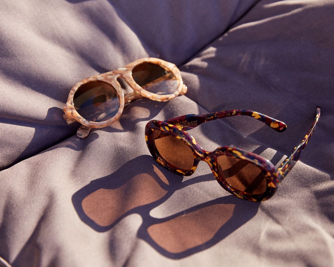 lifestyle image of two pairs of Chloe sunglasses on a sheet in sunlight