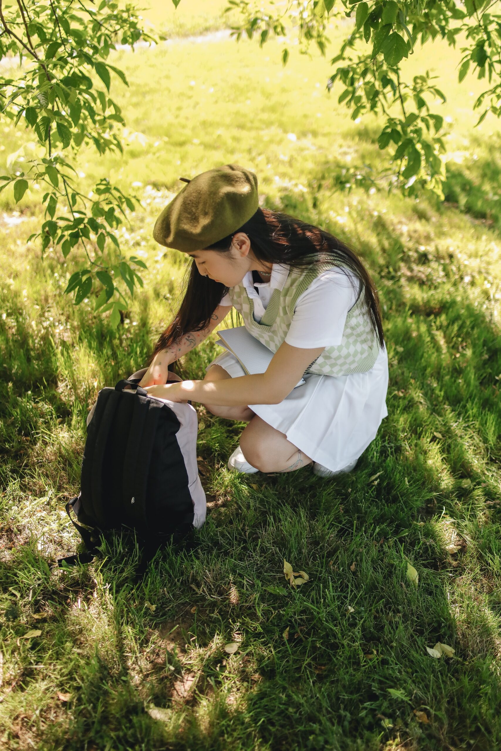 Girl opening a backpack wearing a beret and a green outfit