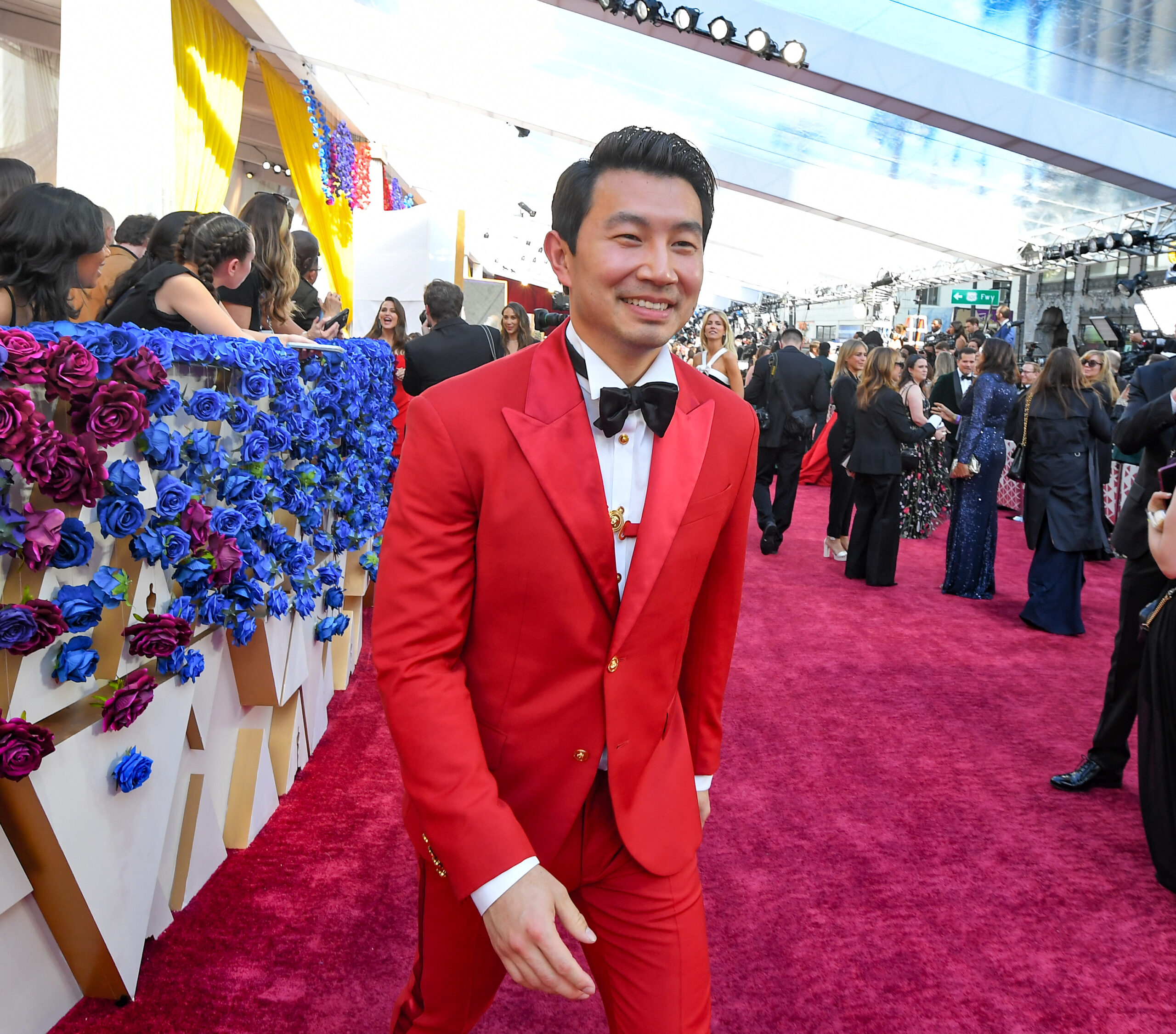 Canadian actor Simu Liu in a red Versace suit, on the red carpet, photographed by George Pimentel.