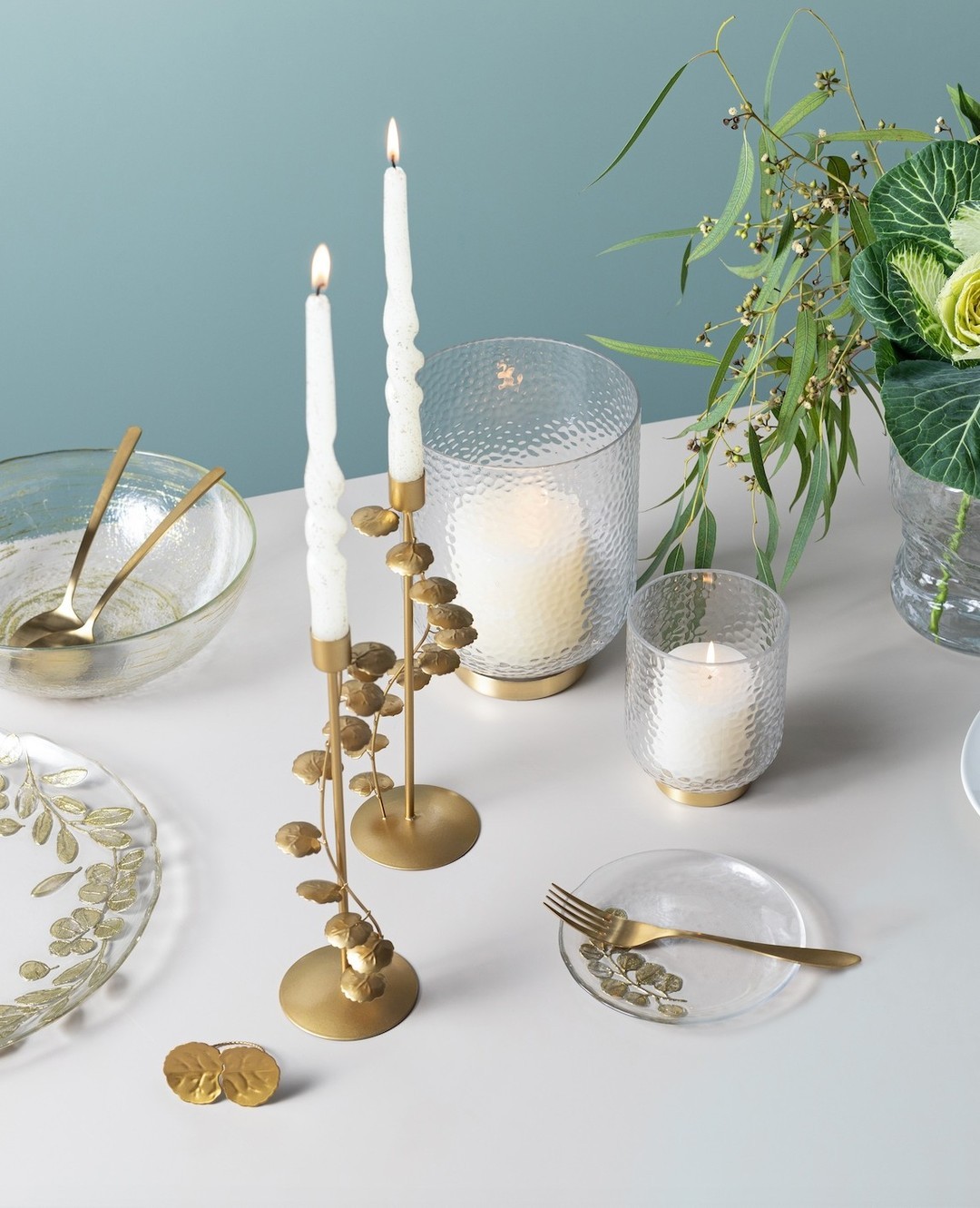 two white candle-sticks lit, with gold accents at the table curated by Fox Home.