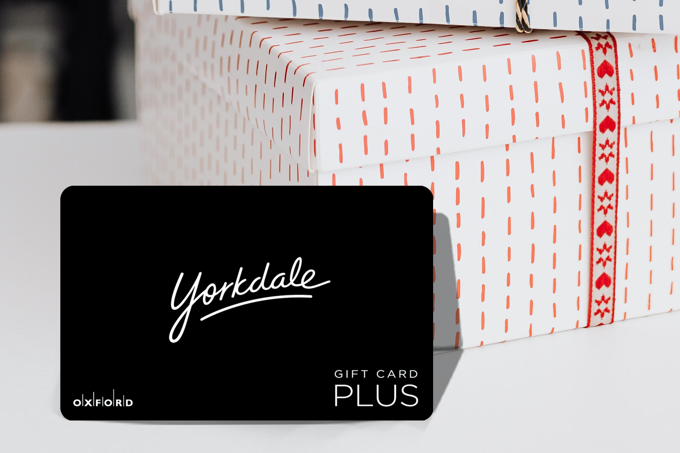 promotional image of a black Yorkdale gift card perched in front of two stacked gift boxes; holiday decor ideas 2023