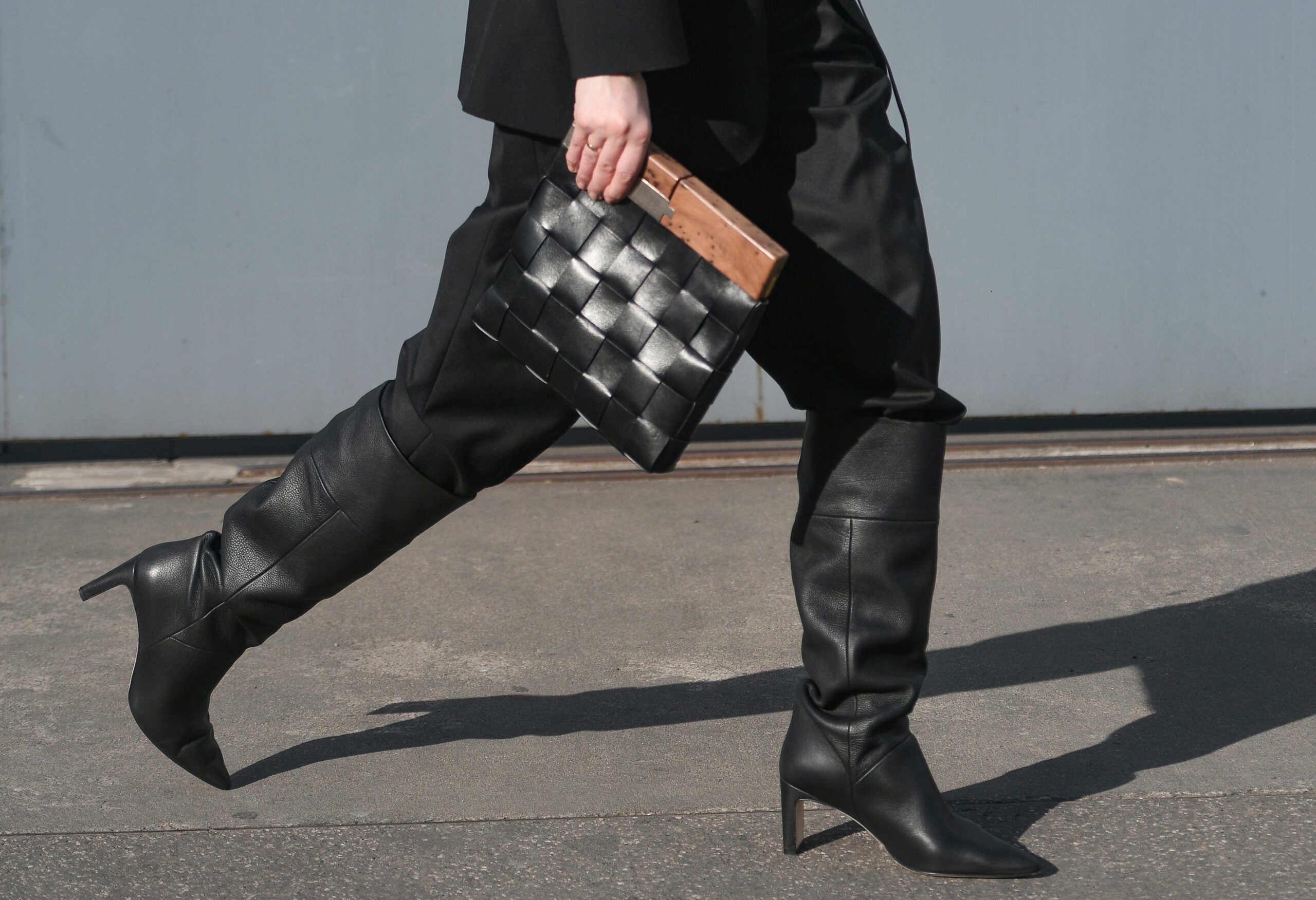 Woman with tall black leather boots and black handbag