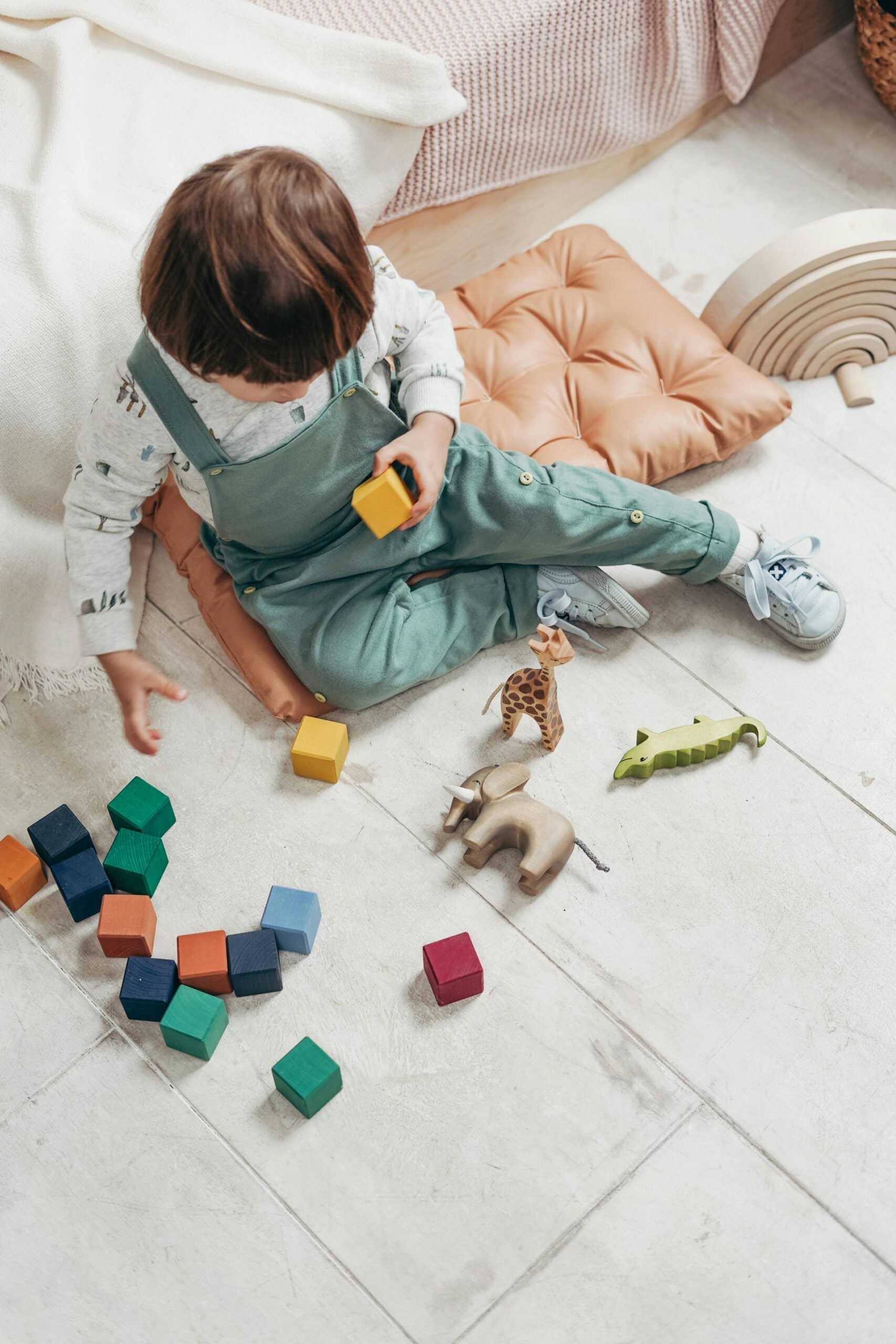 Child in overalls playing with wooden toys