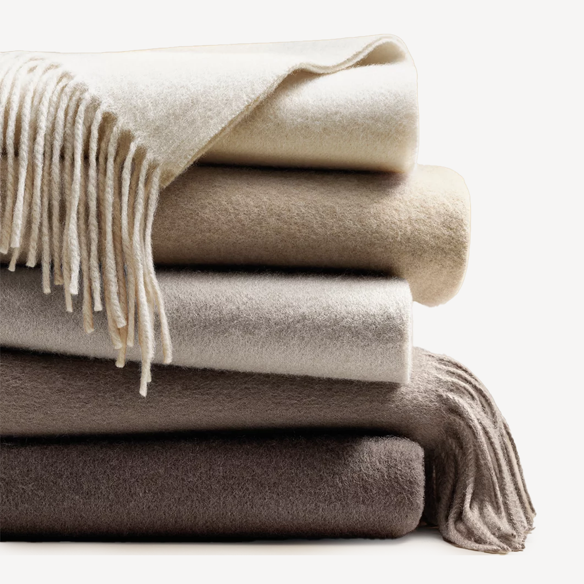 Pile of grey and beige throw blankets with tassels